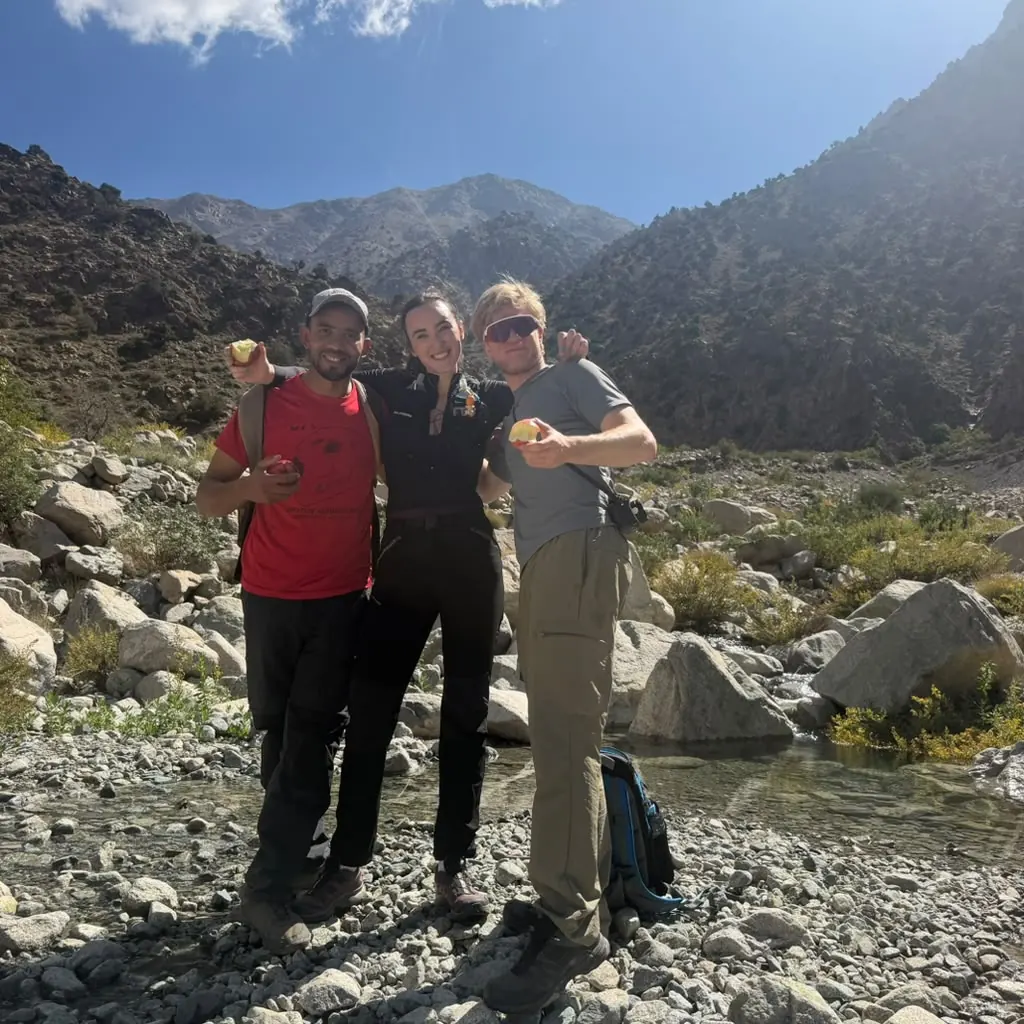 Khalid and two guests sharing apples on a dry riverbed