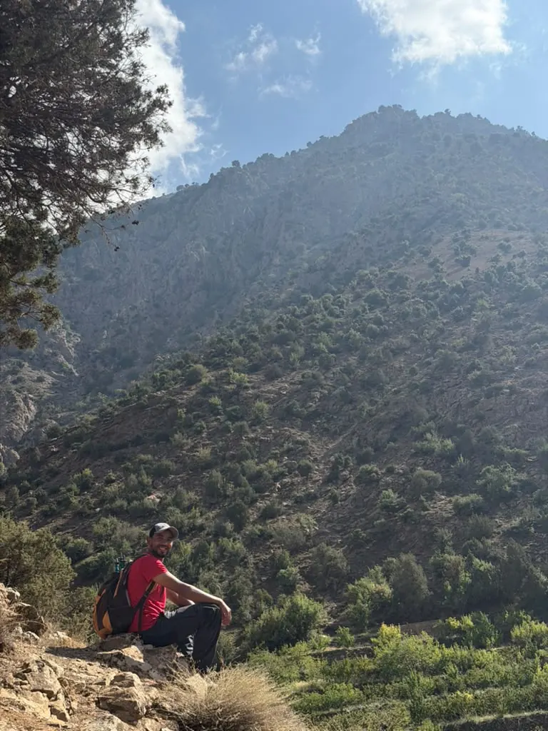 Khalid sitting on a ridge with a big mountain behind him