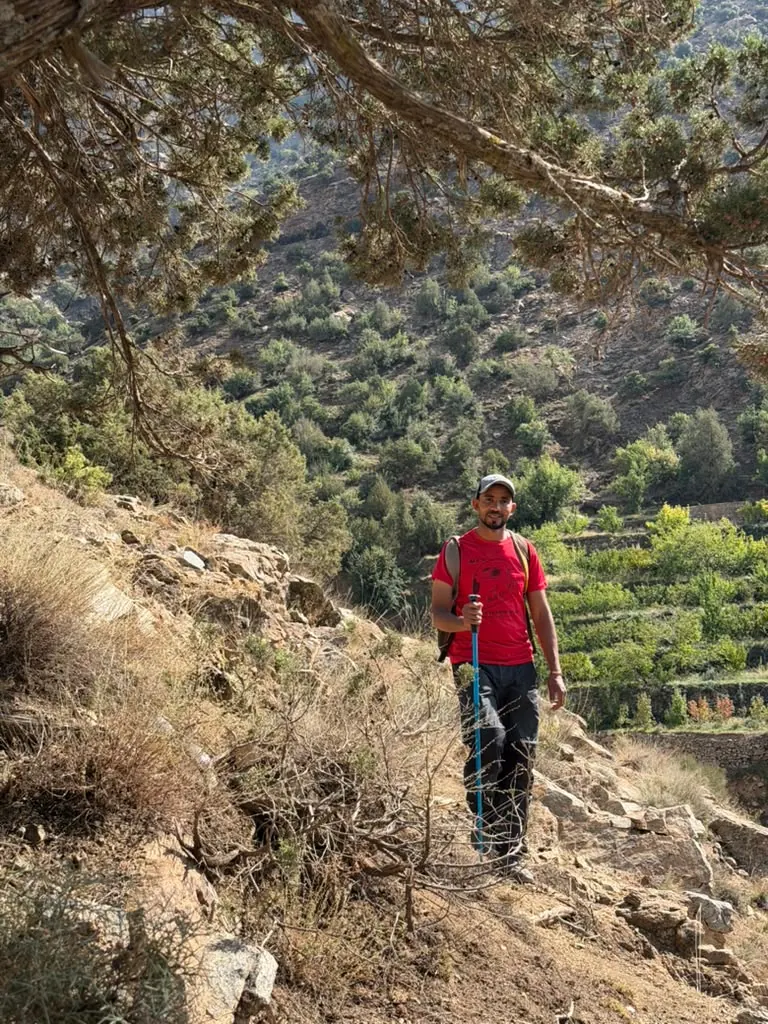 Khalid standing on a mountain trail above green terraced fields