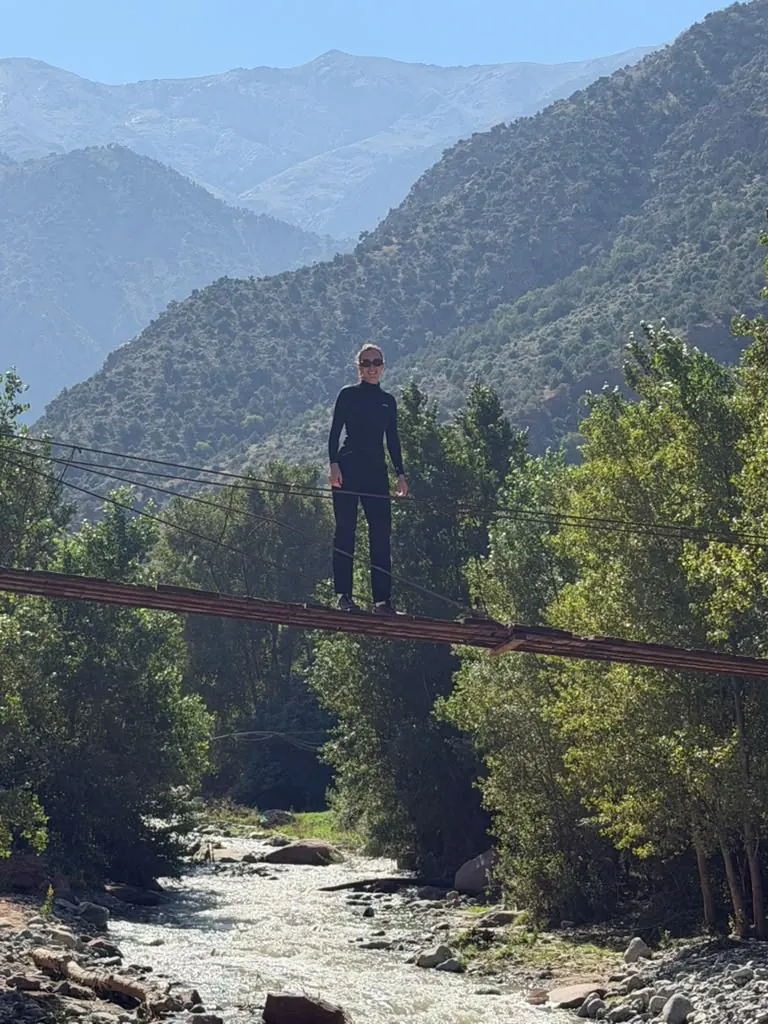A hiker crossing a suspension bridge over the river