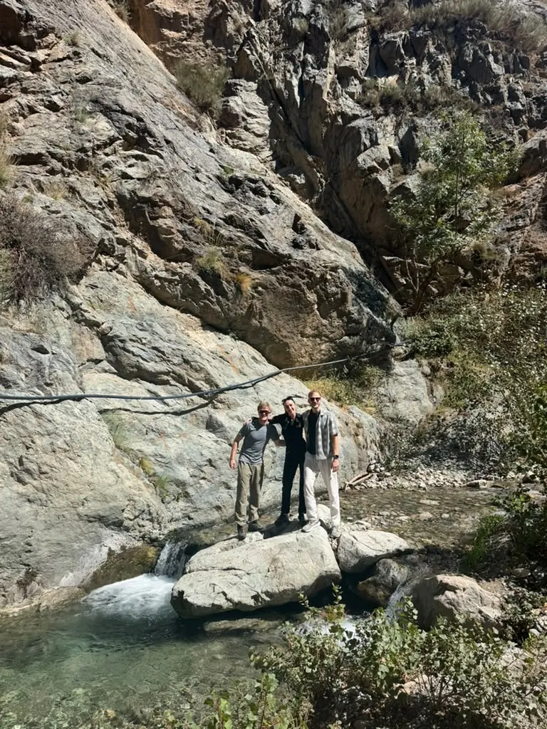 Hikers standing beside a waterfall pool in a rocky gorge
